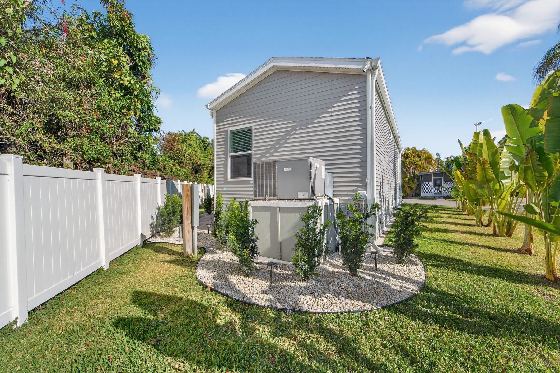 Side of the home with landscaping and white fence