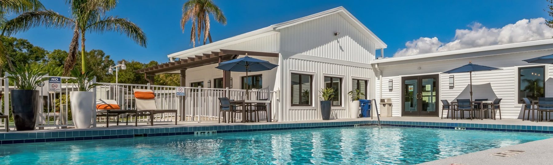 Community pool and clubhouse with palms and blue sky