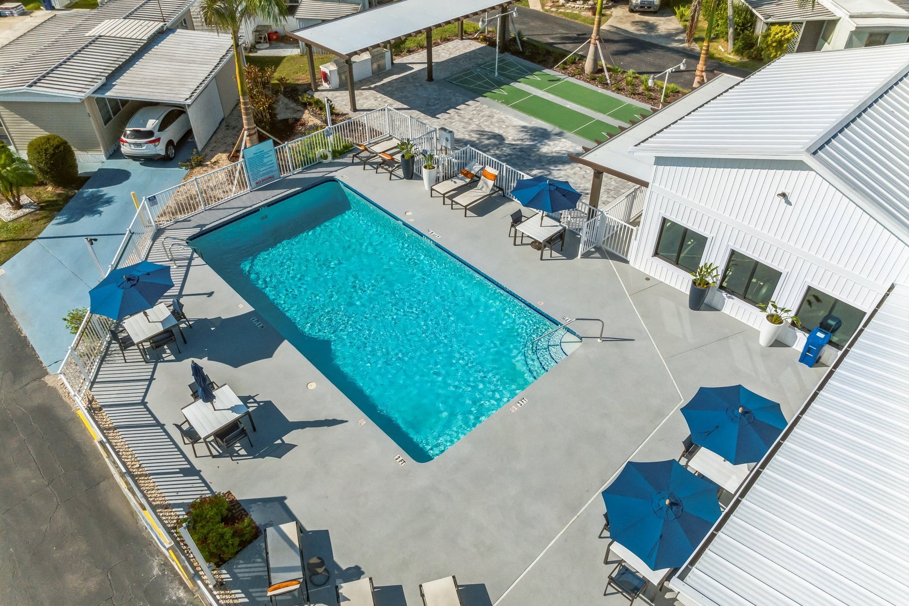 Aerial view of the pool deck, shuffleboard courts, and shaded seating